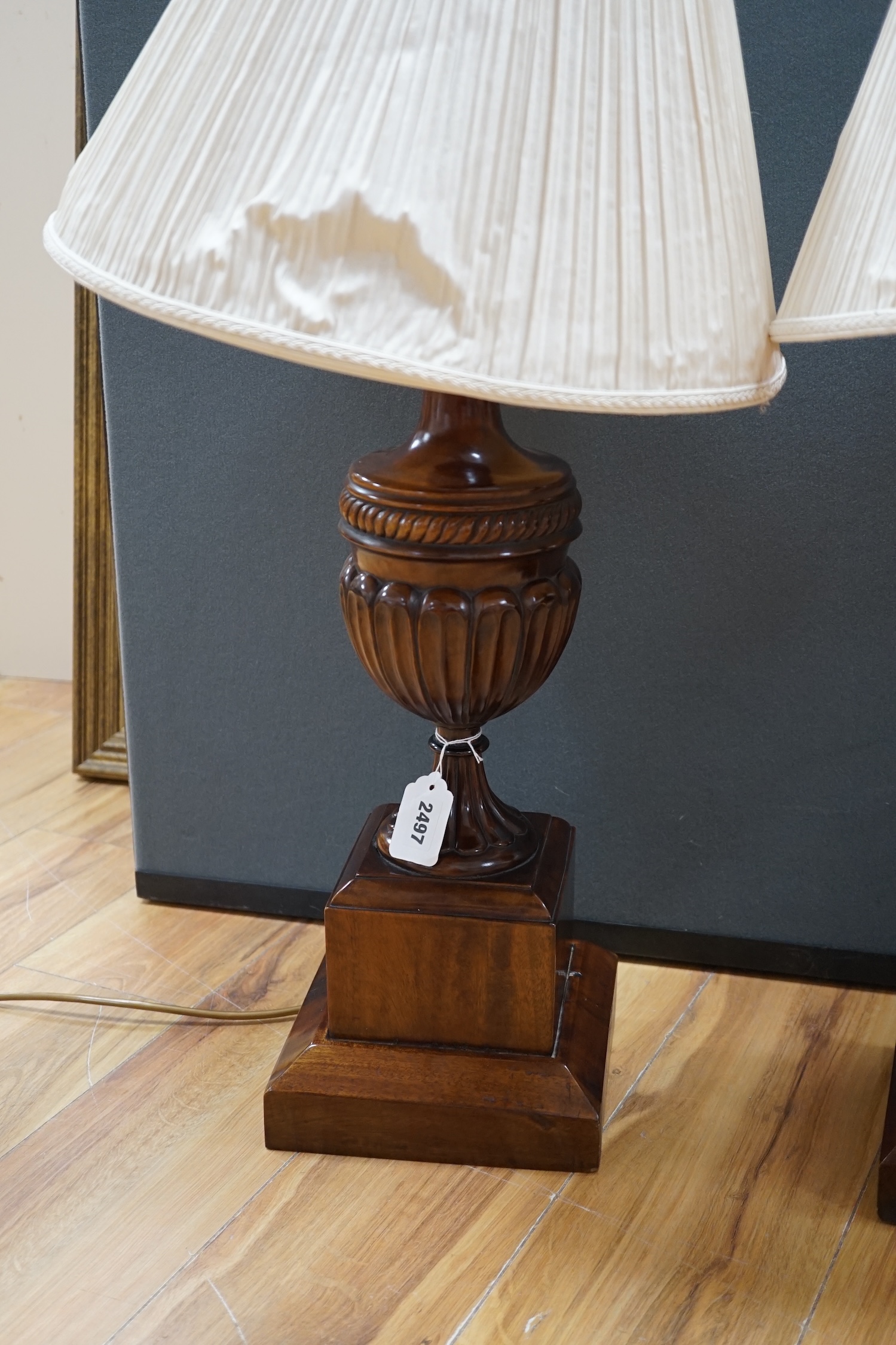 A pair of George III style mahogany carved urn table lamps with shades, 74cm high overall